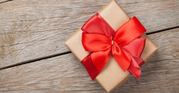 A wrapped present with a red bow on a wooden board 