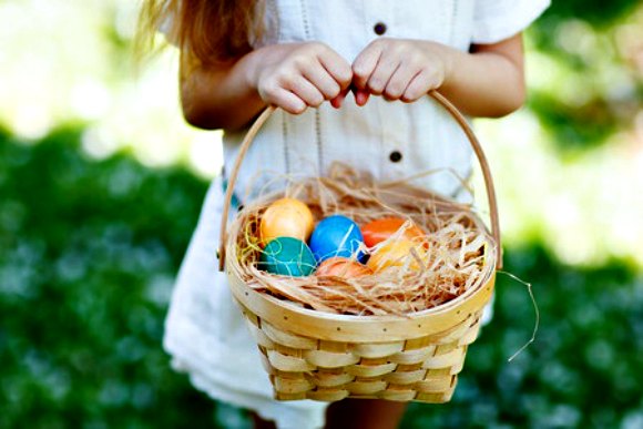 A little girl holding an Easter Basket with Easter eggs in the basket 